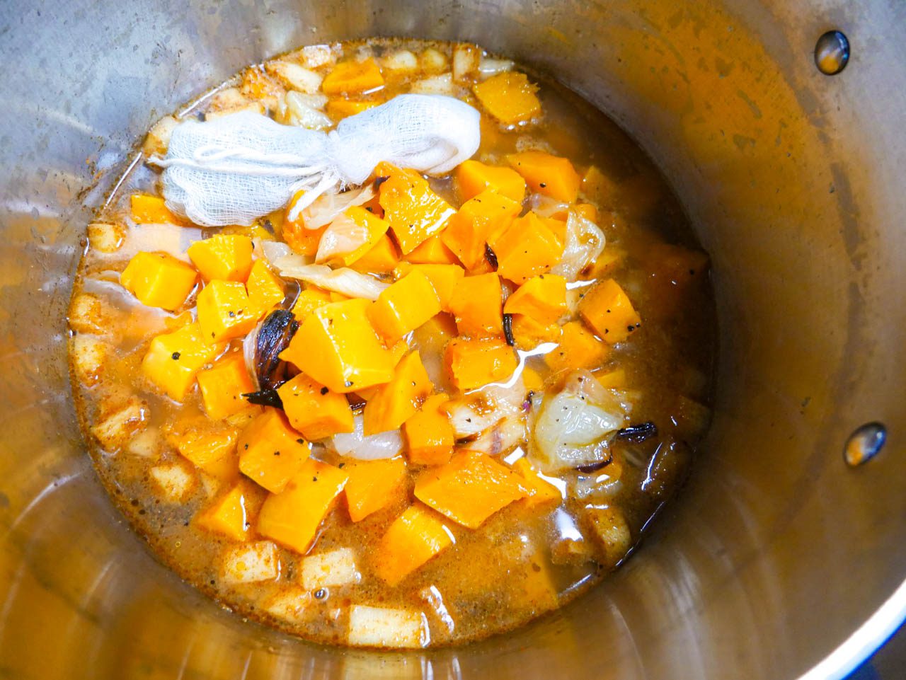 Butternut squash soup ingredients cooking in pot with bouquet garni