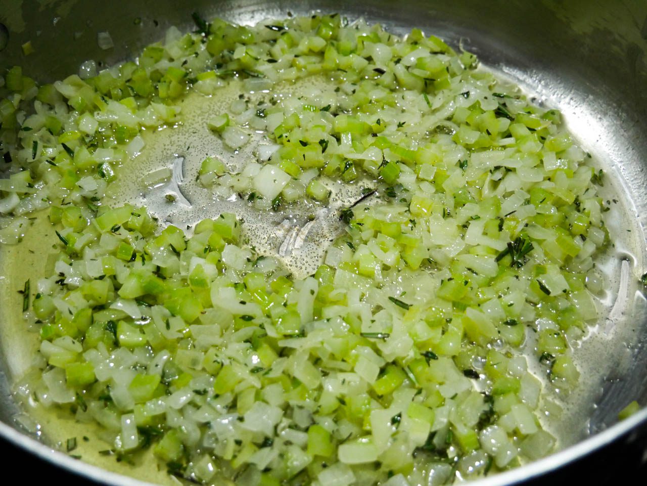 Onions, celery, herbs, butter and salt in pan 