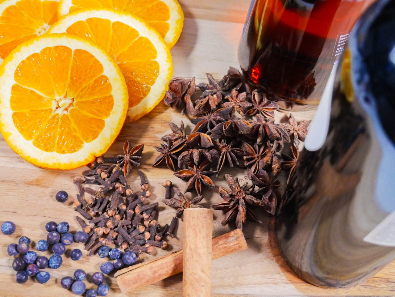 Spices, orange, wine, and brandy on a cutting board.