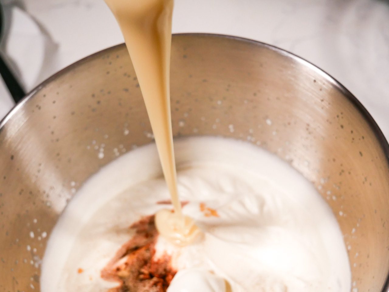 Pouring sweetened condensed milk into the ice cream base