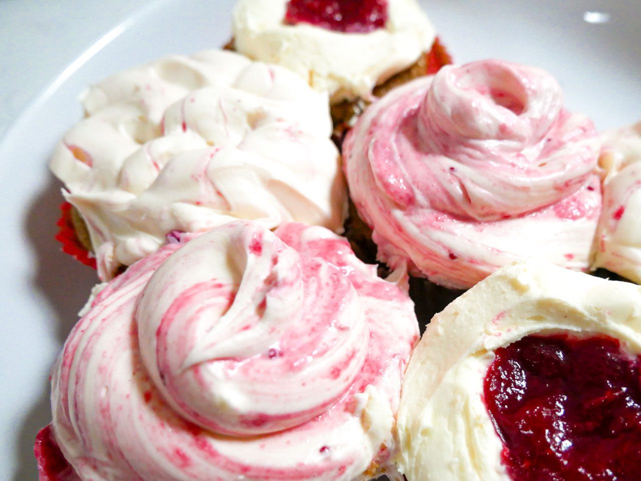 Frosting cranberry gingerbread cupcakes on a plate