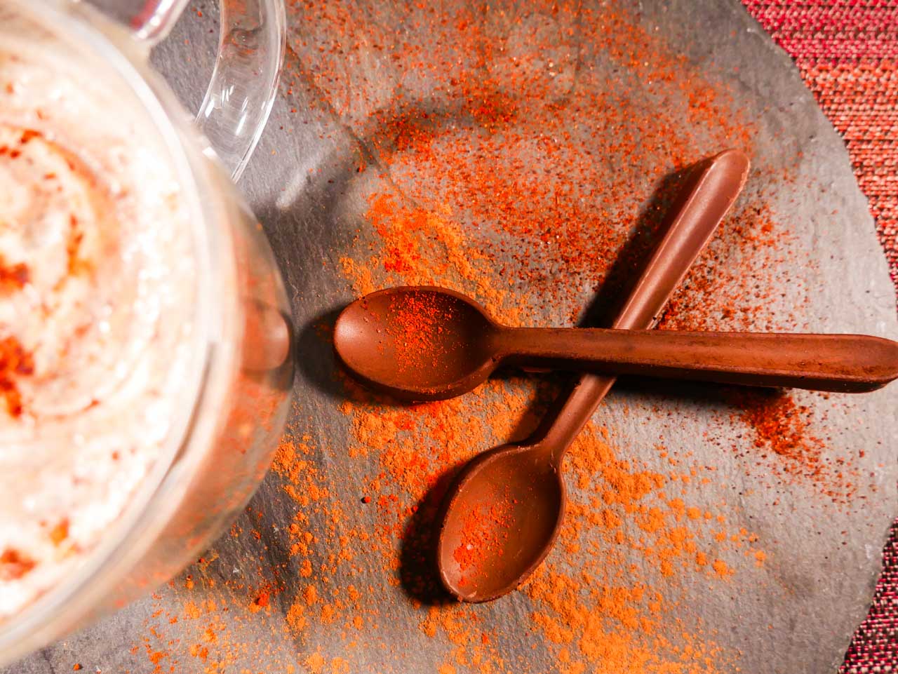 Mexican hot chocolate spoons close up with spices dashed across with hot cocoa
