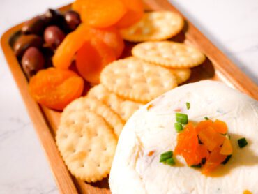 Apricot cheese on a platter with crackers, apricot and olives.