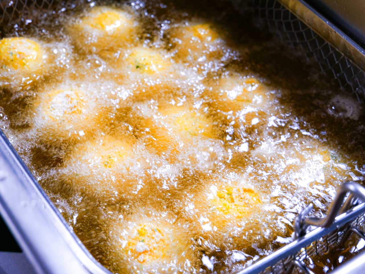 Jalapeno poppers frying in deep fryer basket 