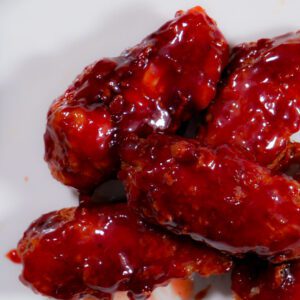 Chicken wings in a bowl coated in sweet sriracha sauce