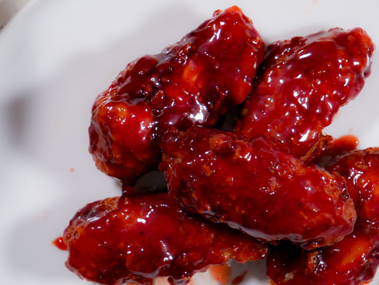 Chicken wings in a bowl coated in sweet sriracha sauce