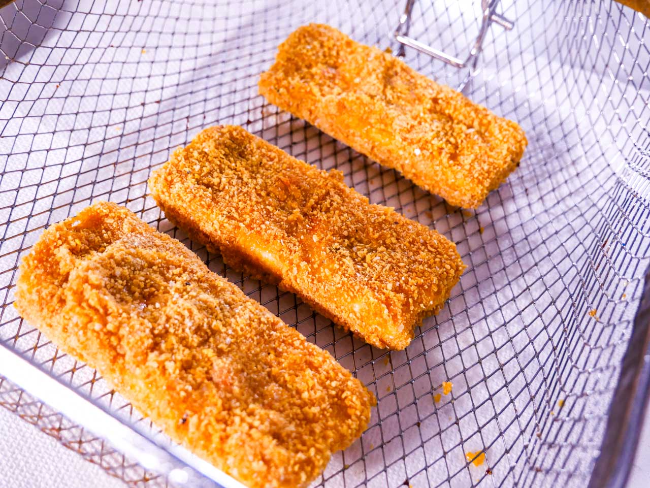 Breaded Mozzarella Sticks in deep fryer basket, pre-fry.
