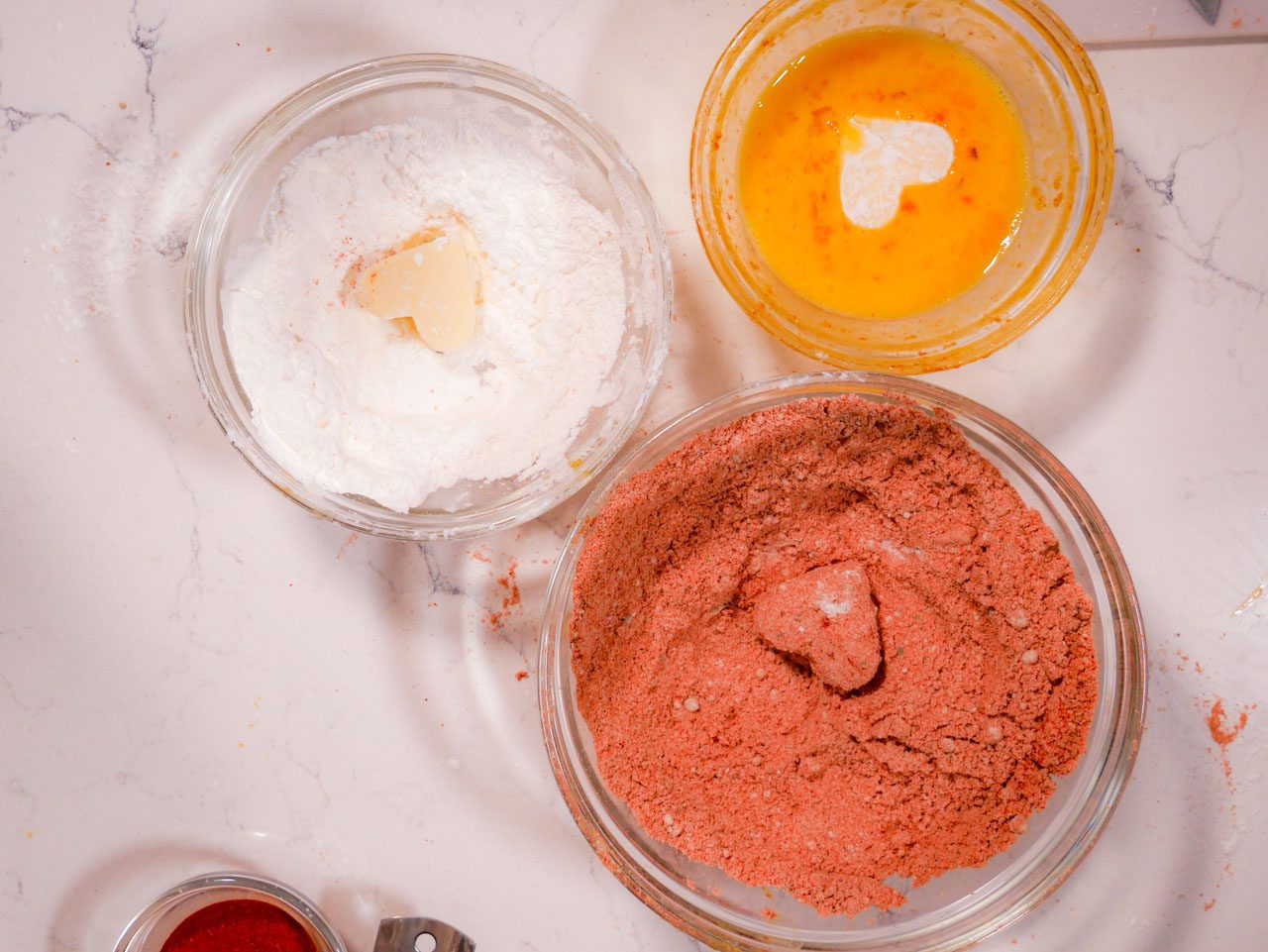 Breading the mozzarella hearts in corn starch, egg, and flour mixture in three bowls 