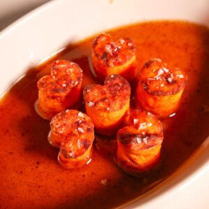 Sweet Potatoes Fondant in a white serving dish surrounded by the reduced butter and maple syrup sauce