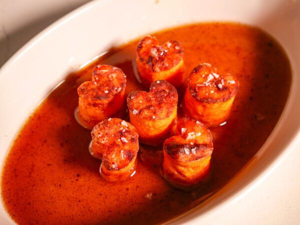 Sweet Potatoes Fondant in a white serving dish surrounded by the reduced butter and maple syrup sauce