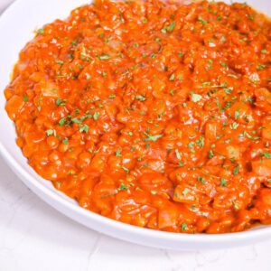 Hearty Savory Breakfast Lentils in a white bowl with parsley sprinkled on top. Bowl sits on a white countertop