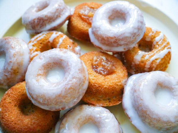 Mini donuts or mini bundts with floral glaze and apple pie filling arranged on a light yellow dish