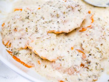 Creamy sage parmesan sauce over butternut squash ravioli in a white bowl on a countertop.