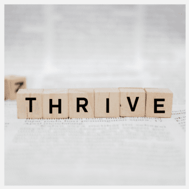 Wooden block letters that spell thrive against a white and grey background - the best jobs for a highly sensitive person to thrive in.