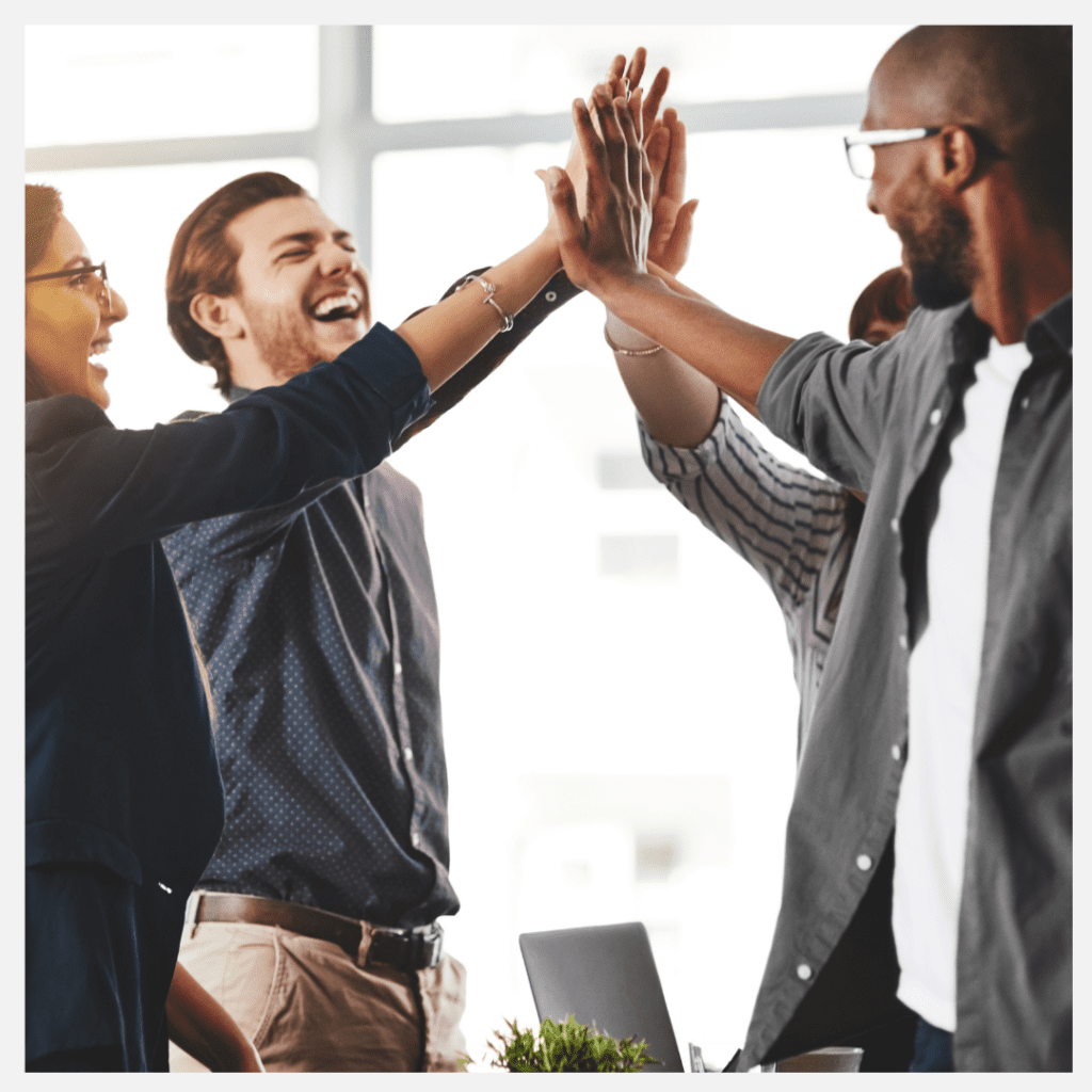 Group of people high-fiving with their hands in the middle, all smiling in a circle to indicate the best jobs for a highly sensitive person. 