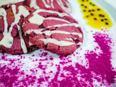 Vibrant magenta Dragon Fruit Cookies With Passion Fruit Glaze on a white plate