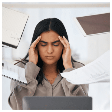 Woman being bombarded with papers, charts in front of her laptop. She is overwhelmed. Worst jobs for a highly sensitive person