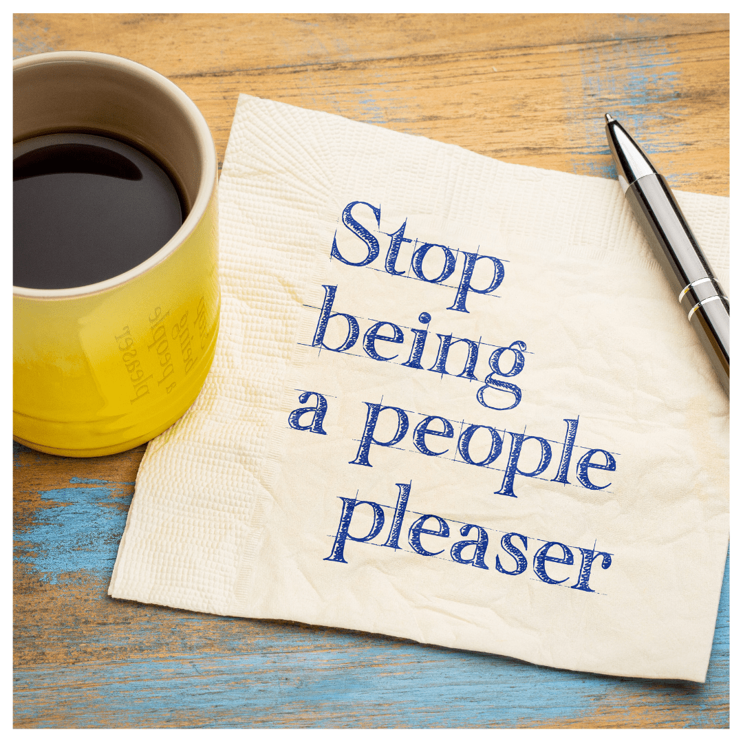 "Stop being a people pleaser" was written on a napkin next to a metal pen and a yellow coffee mug with coffee. On top of a wood desk.