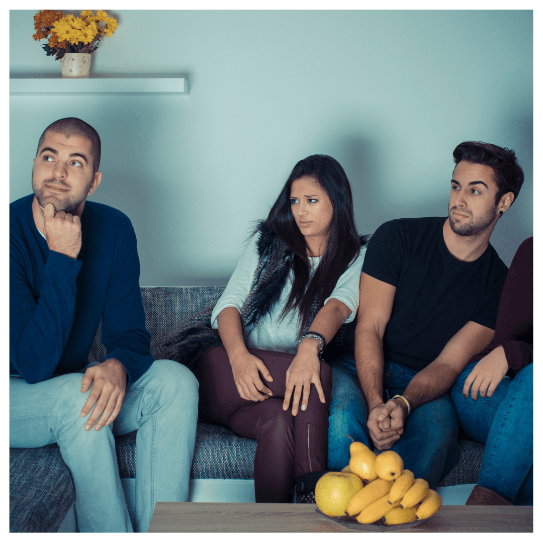 Friends on a couch leaning away in judgment from an individual in an arm chair in a dimly lit room in front of a TV