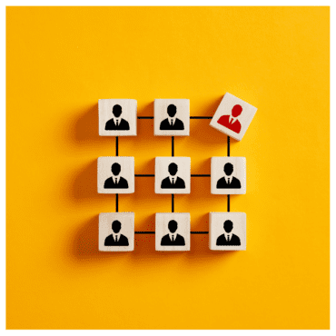 Yellow background and wooden blocks with black silhouettes of a head and shoulders in a grid. One block is tilted to the side and is red.