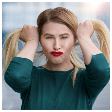 4 Types of Emotionally Immature Parents - a woman grabbing her hair on either side, puckering her face to make a silly expression in a green shirt against a gray background