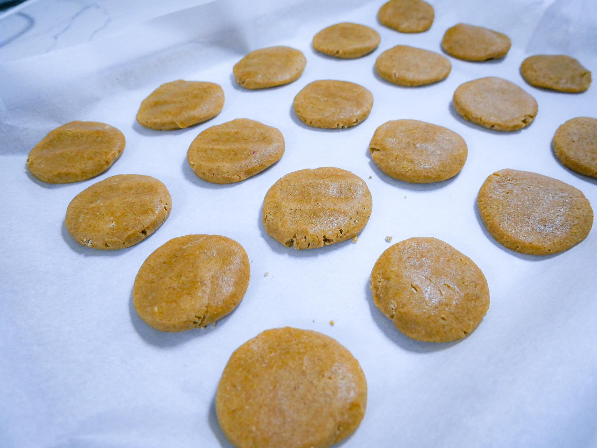 Mango lassi cookie dough flattened on parchment for individual cookies