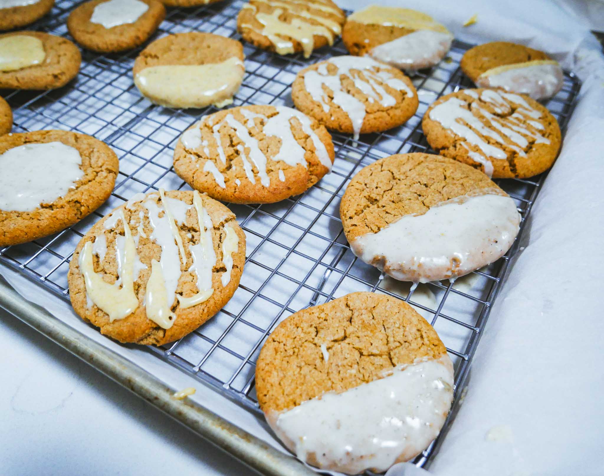 Mango Lassi cookies decorated on a wire rack over parchment paper on a baking sheet atop a white countertop.