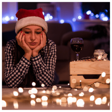 A girl with a santa hat looking sad at a table covered in string lights